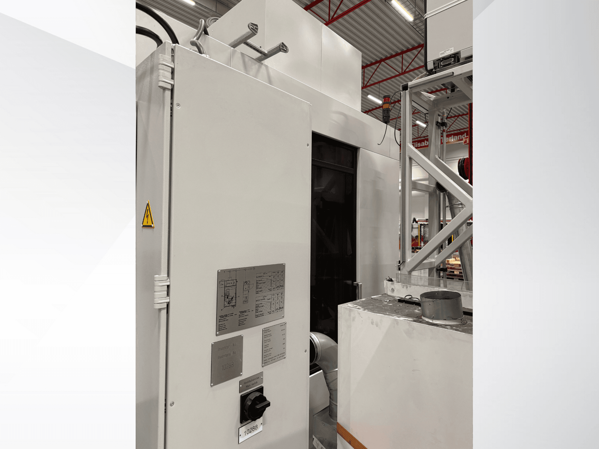 Vista lateral de una máquina industrial blanca con panel de control y etiqueta de advertencia, parte de un sistema automatizado.