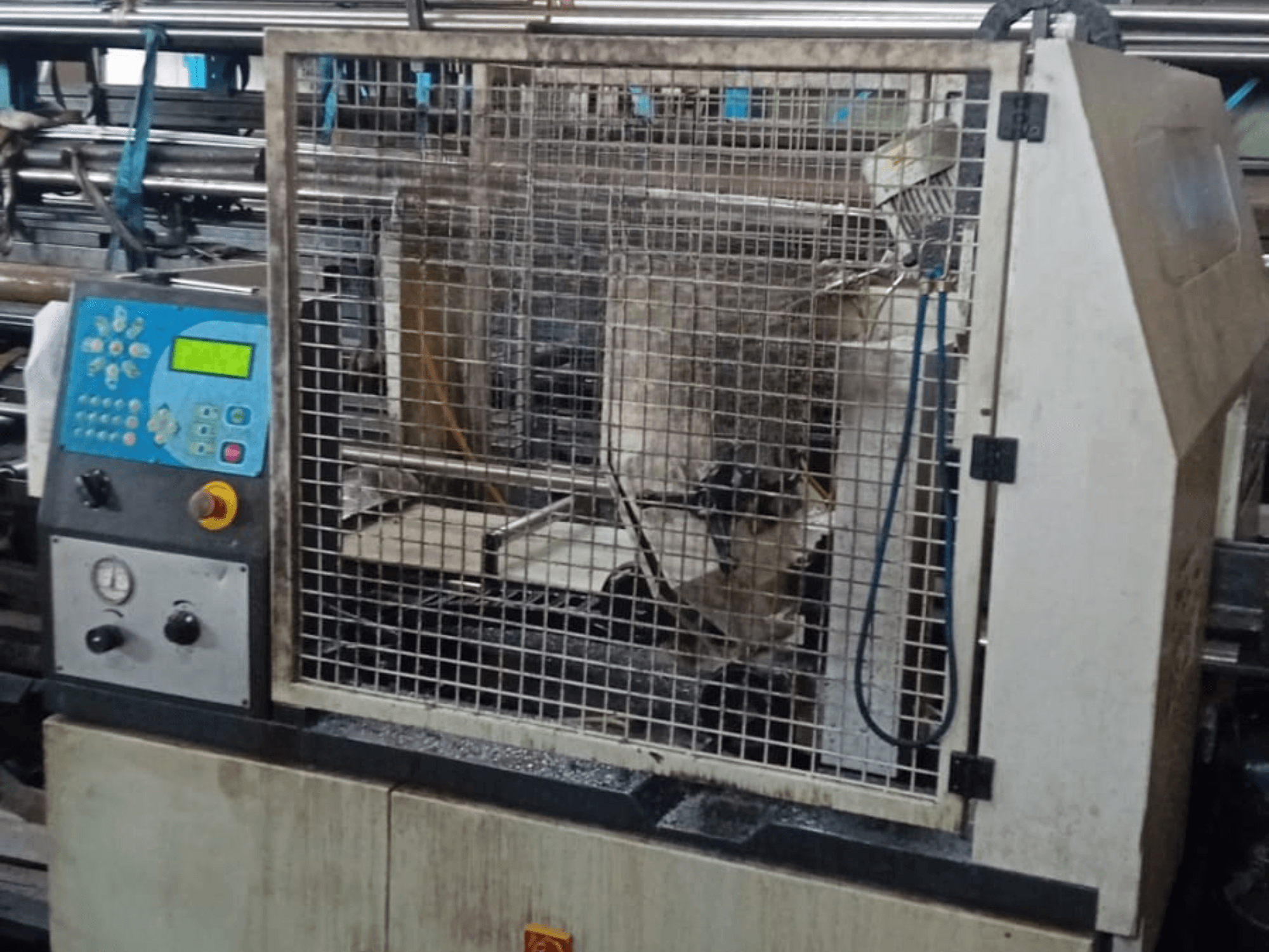 Sierra de cinta para metal Macc 381 AV, vista frontal, mostrando el panel de control, la jaula de seguridad y los restos de metalistería en la base.