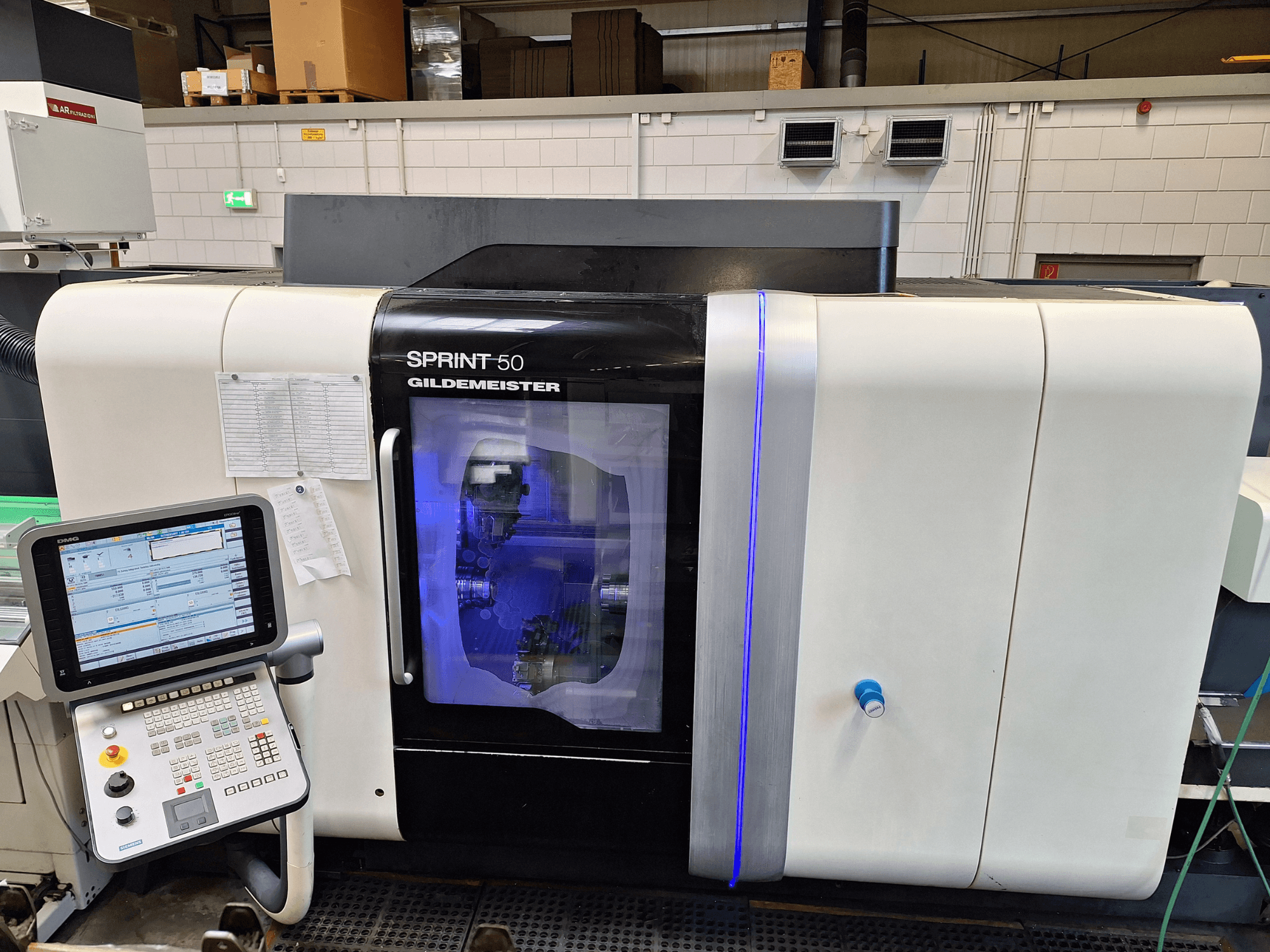 DMG Sprint 50 2T máquina de torneado horizontal, vista frontal, con panel de control y carcasa transparente que muestra la maquinaria interior.