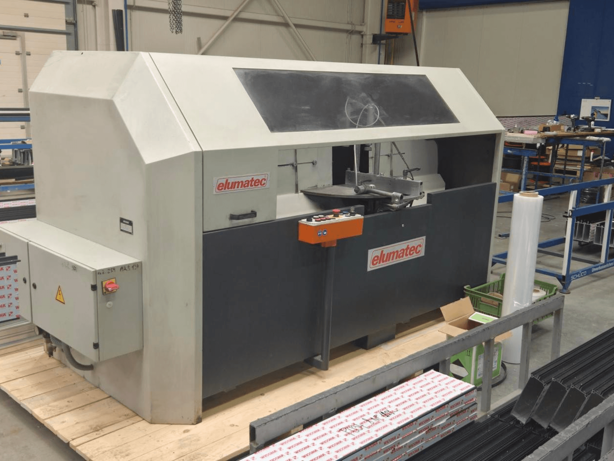 Sierra circular para metal Elumatec AKS 134, vista frontal, mostrando el panel de control y la zona de corte sobre una plataforma de madera.