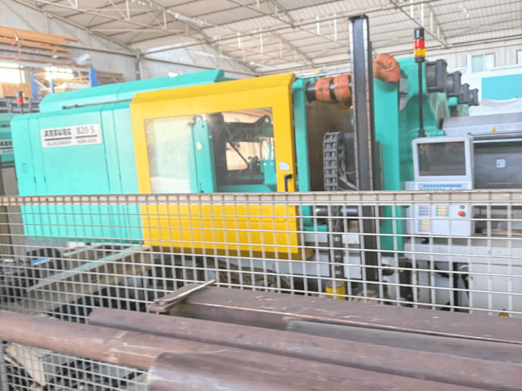 Máquina de moldeo por inyección hidráulica Arburg SELECTA 820 S 4000-3200, vista lateral, mostrando el panel de control y el vibrante diseño amarillo y verde azulado.