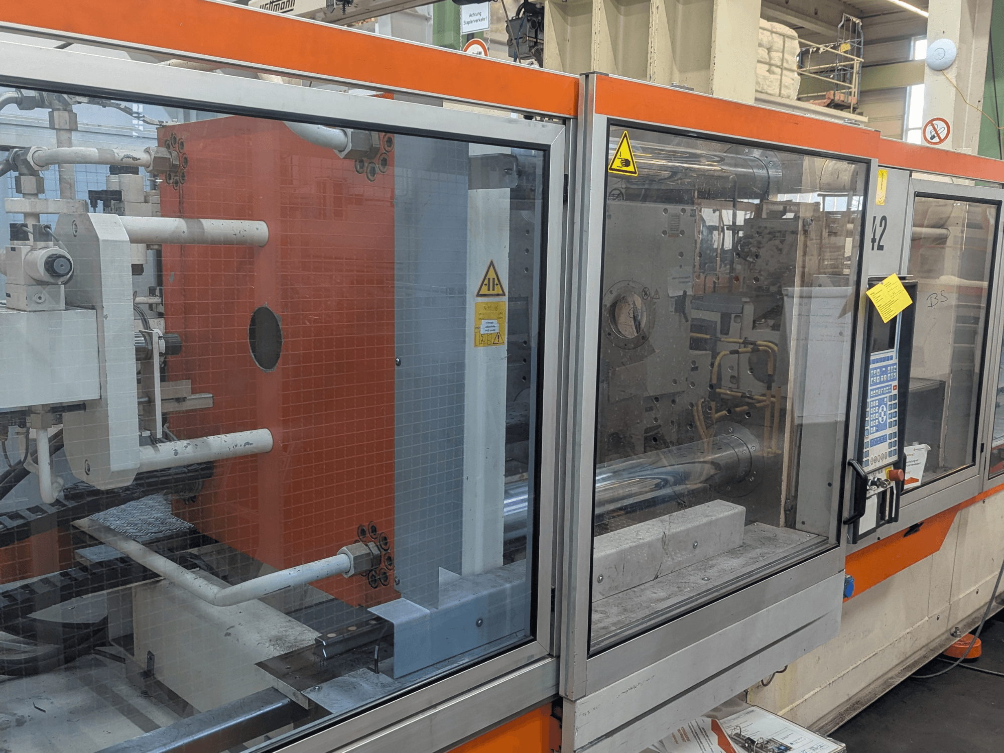 Vista frontal de una máquina de moldeo por inyección hidráulica DEMAG SYSTEC 80/420-310 con panel de control visible y componentes de la maquinaria.