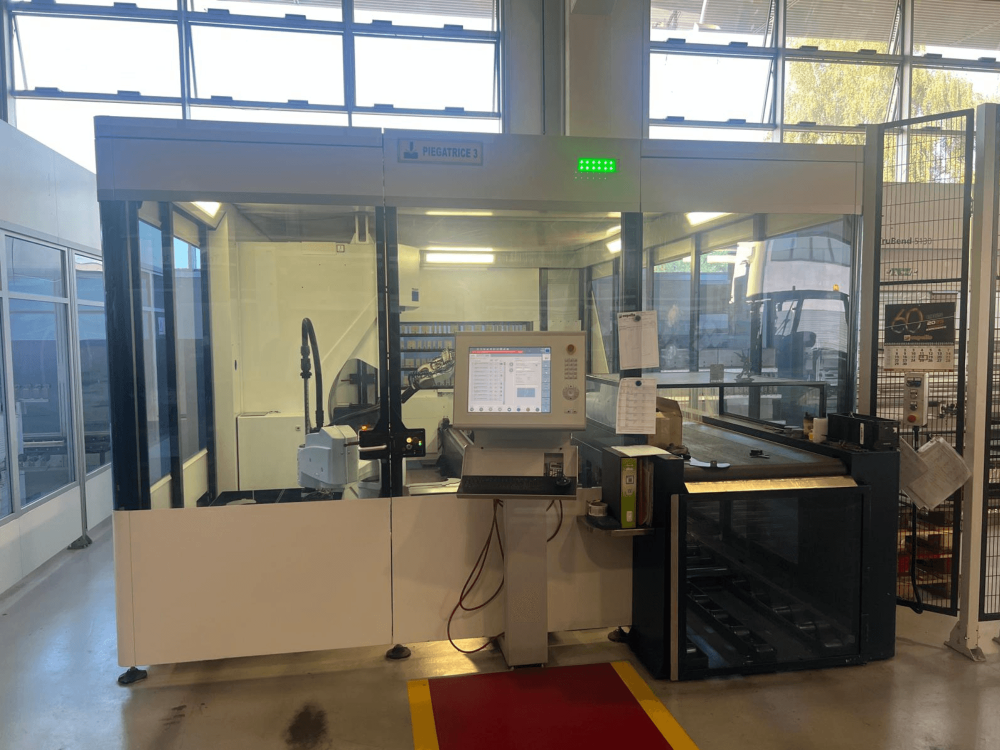 Plegadora industrial, modelo Piegatrice 3, vista frontal con panel de control y brazo robótico, en un taller bien iluminado.