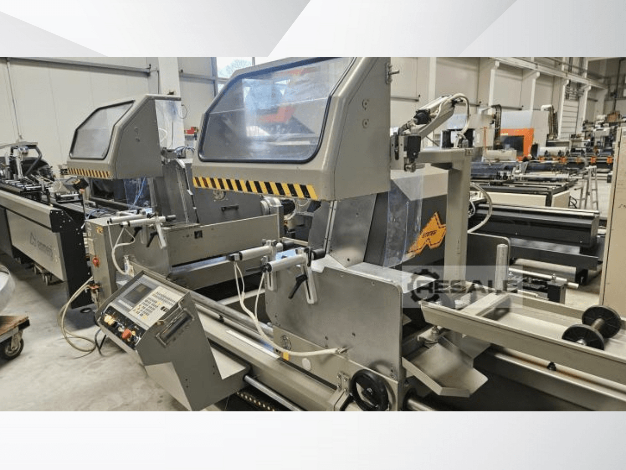 Máquinas de doble sierra en un entorno de fábrica; vista frontal que muestra el panel de control, las cubiertas de cristal y los componentes de corte.