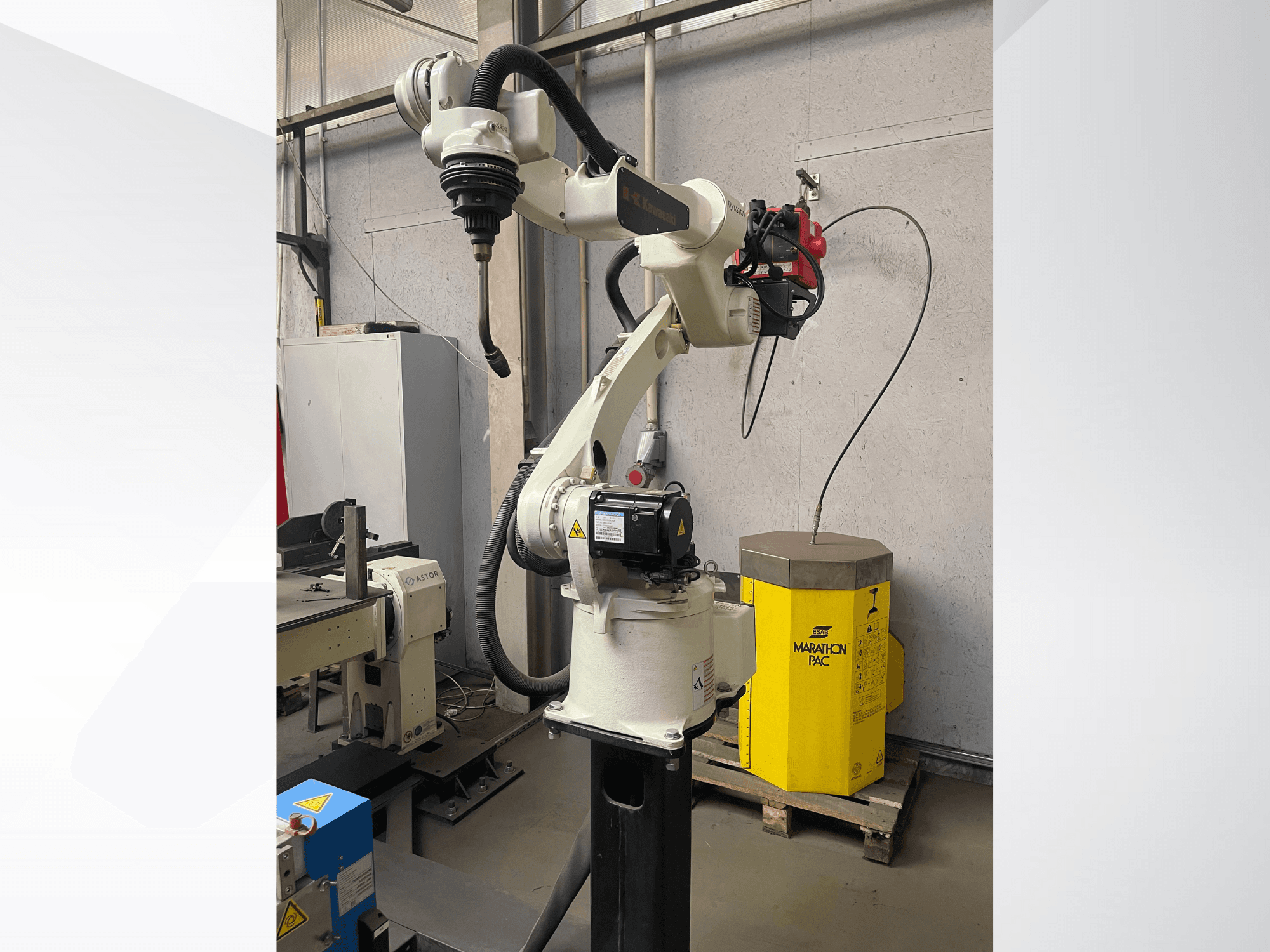 Kawasaki robotic arm from a side view, featuring a mounted tool holder, with a yellow power unit in the background.