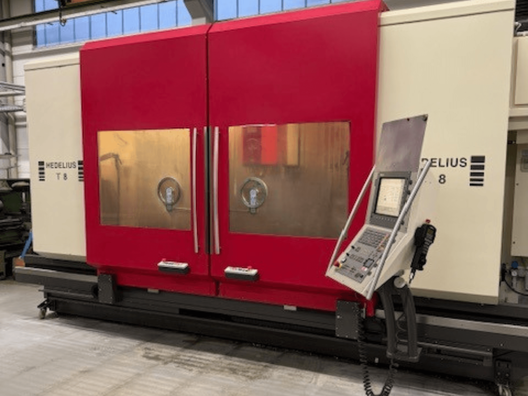 Máquina CNC HEDELIUS T8 en vista frontal, con puertas rojas, panel de control y visibilidad de los componentes internos.
