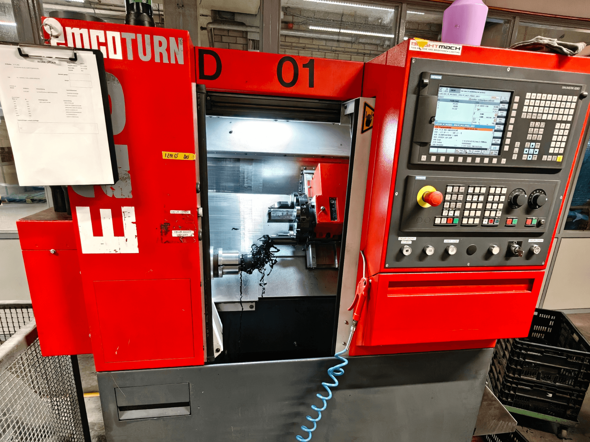 Vista frontal del torno horizontal EMCO TURN E25, con controles de funcionamiento, portaherramientas y área de trabajo con virutas.