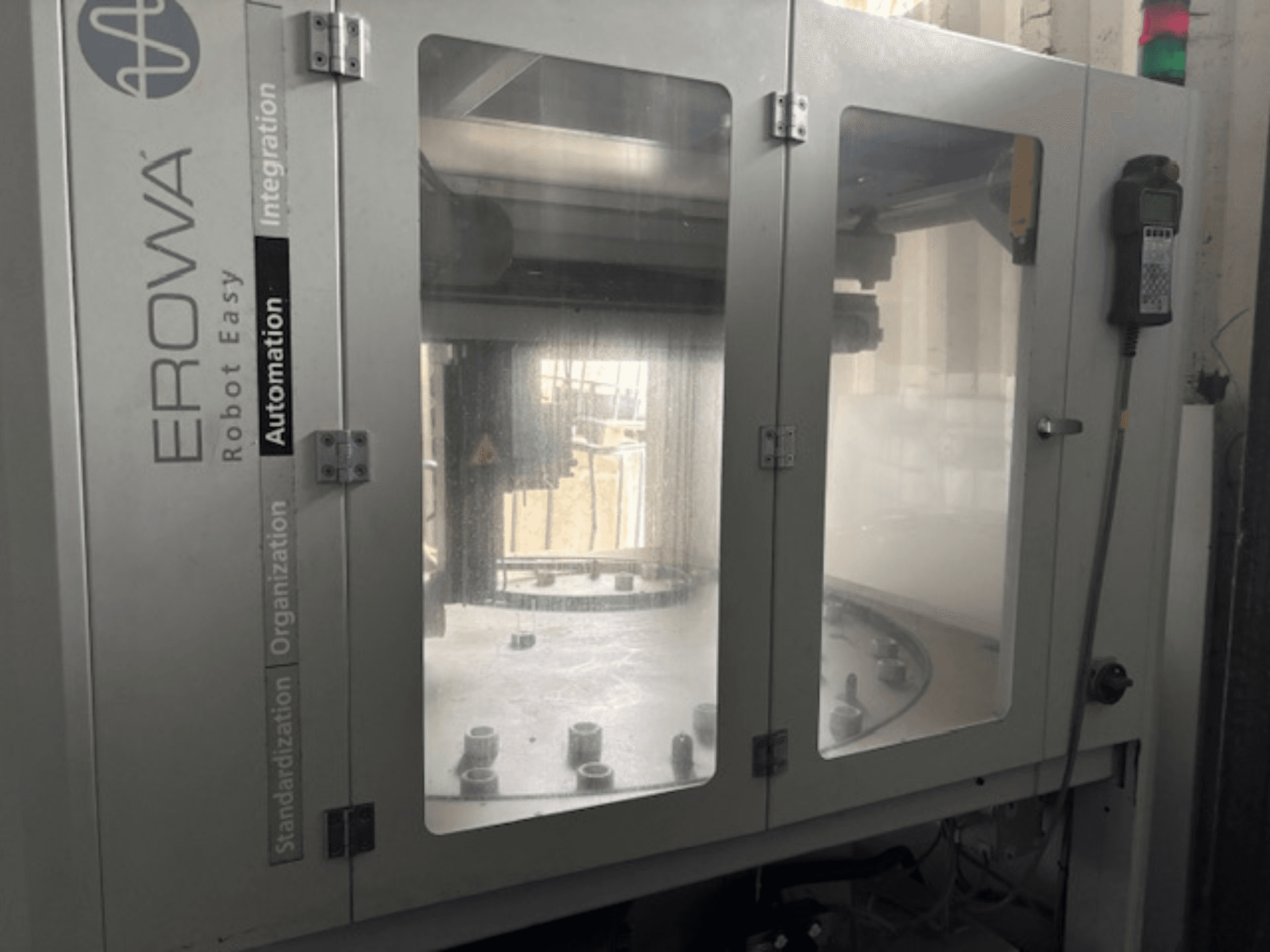 Vista frontal del EROWA Robot Easy Automation; presenta puertas transparentes, componentes de automatización visibles y panel de control.