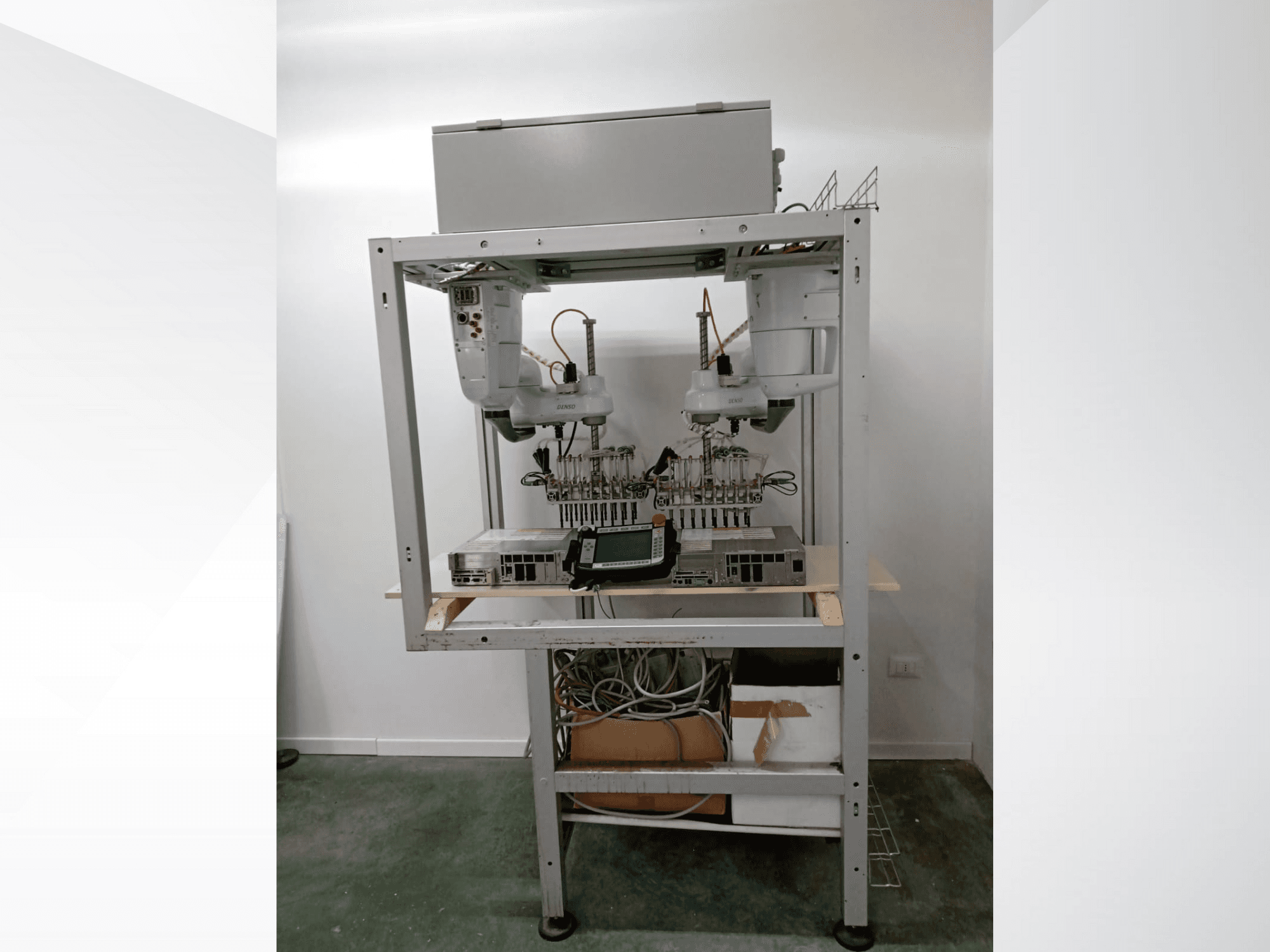 Automated robotic workstation with dual arms, display unit, and electronics on a metal frame, front view, advanced technology setup.