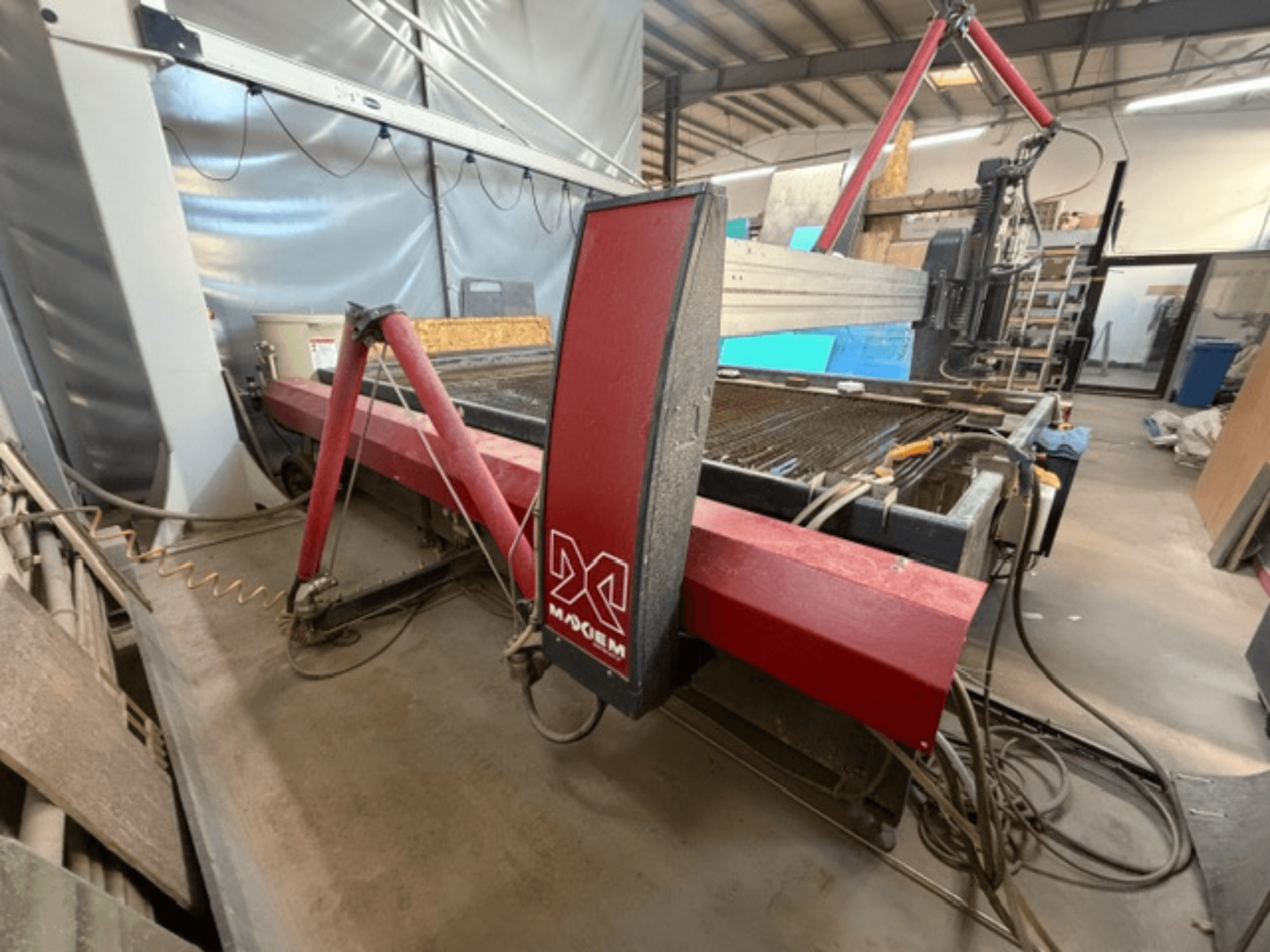 Máquina de corte por chorro de agua roja de la marca X, vista lateralmente, mostrando los componentes mecánicos y los detalles de las tuberías.