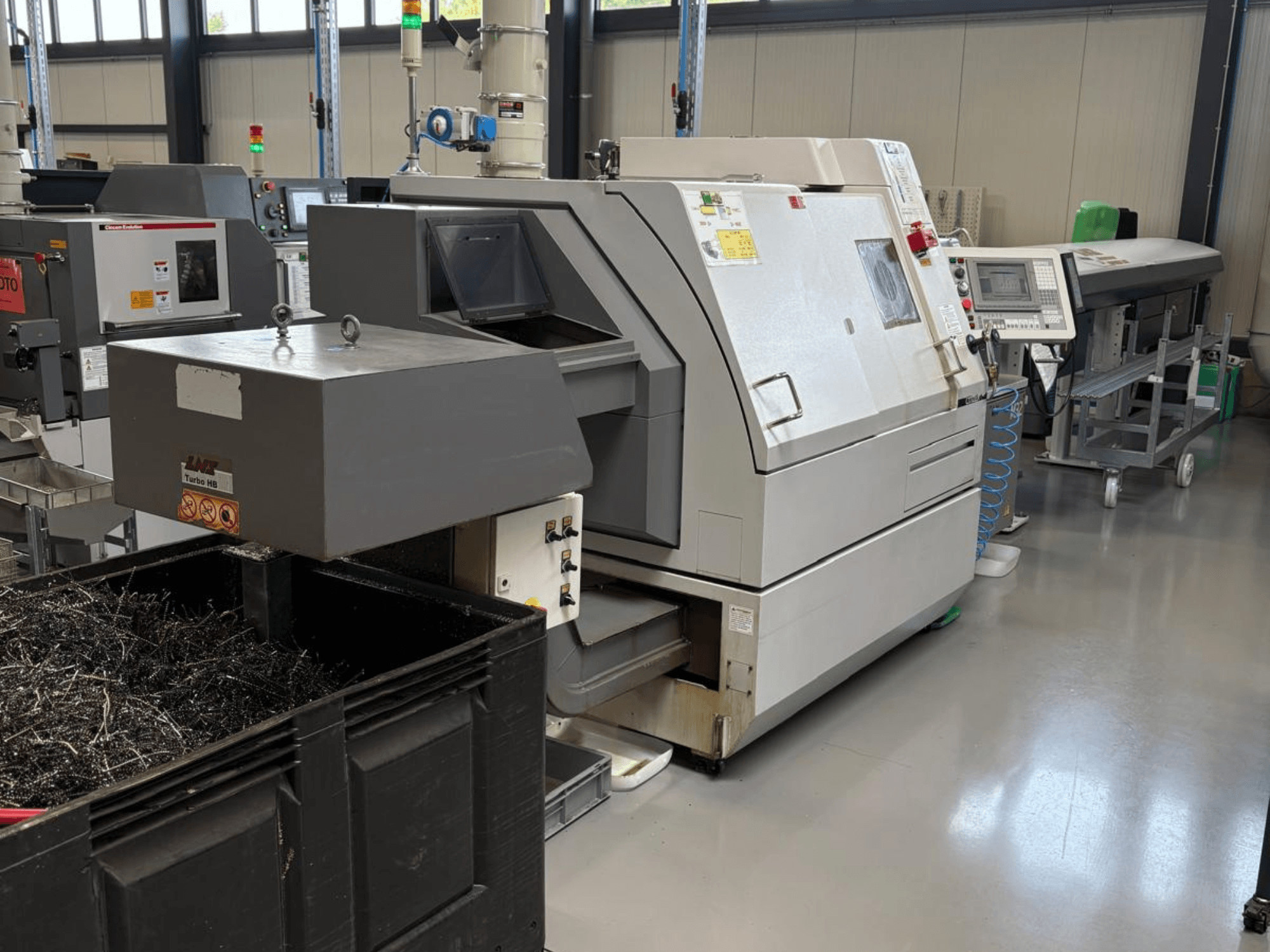 Máquina industrial LTA Turbo H8, vista lateral, con un gran contenedor para virutas de metal y panel de control en una fábrica.