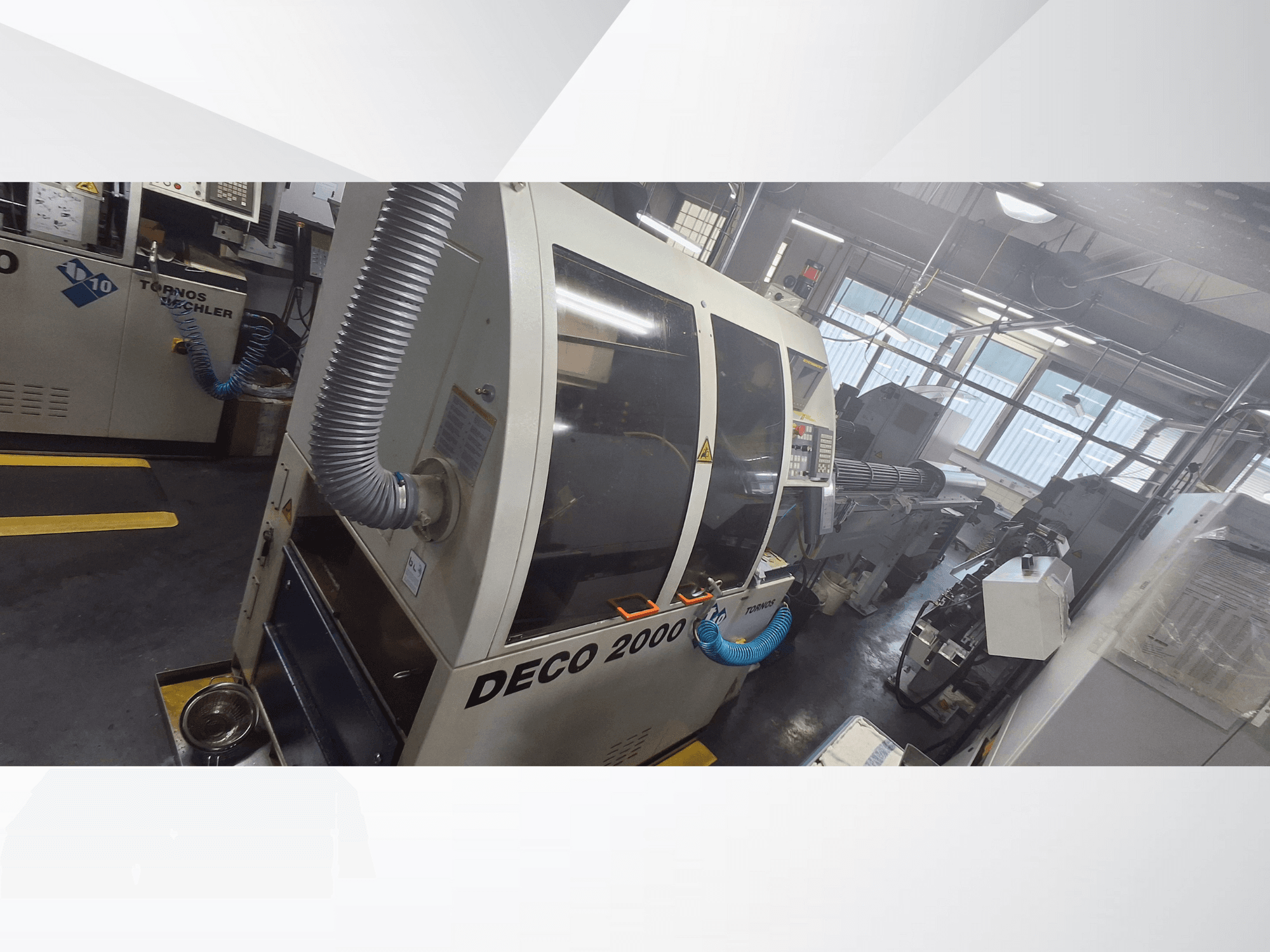 Máquina CNC DECO 2000 en taller, vista frontal, con manguera de ventilación y panel de control, diseñada para el mecanizado de precisión.