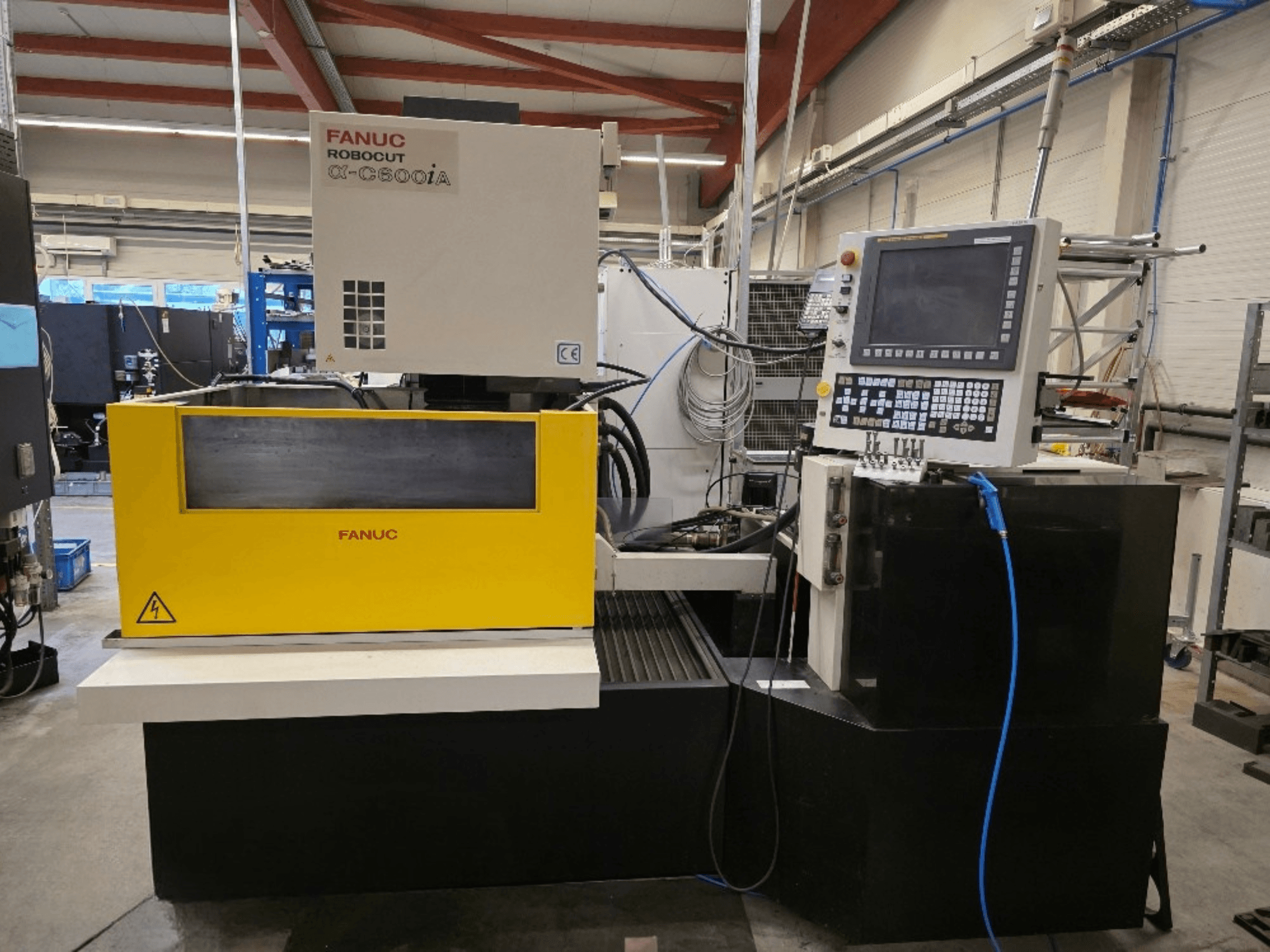 Cortadora de hilo FANUC Robocut α-C600iA, vista frontal, con panel de control amarillo y pantalla digital.