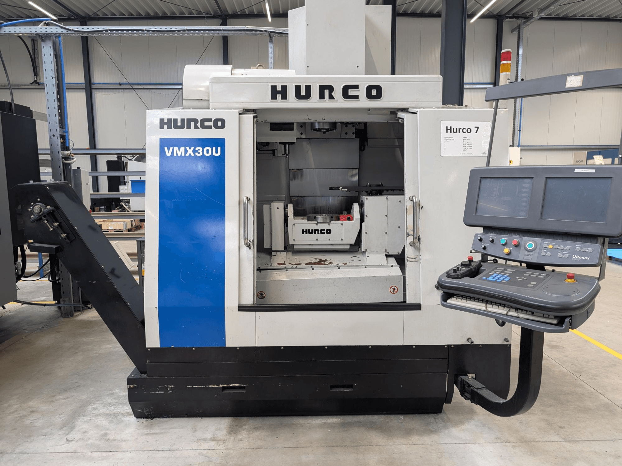 Máquina CNC Hurco VMX30U en vista frontal con panel de control; cuenta con un interior espacioso y una interfaz de control de precisión.