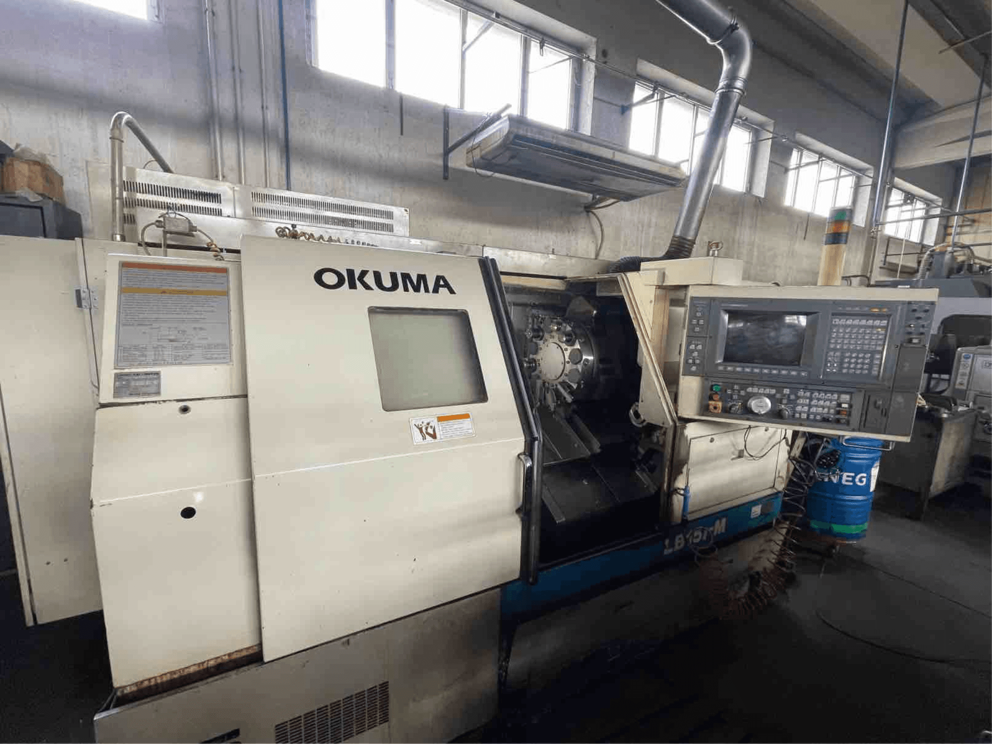 Torno horizontal Okuma LB15i-M, vista frontal; presenta panel de control y zona de herramientas de corte con indicadores detallados.