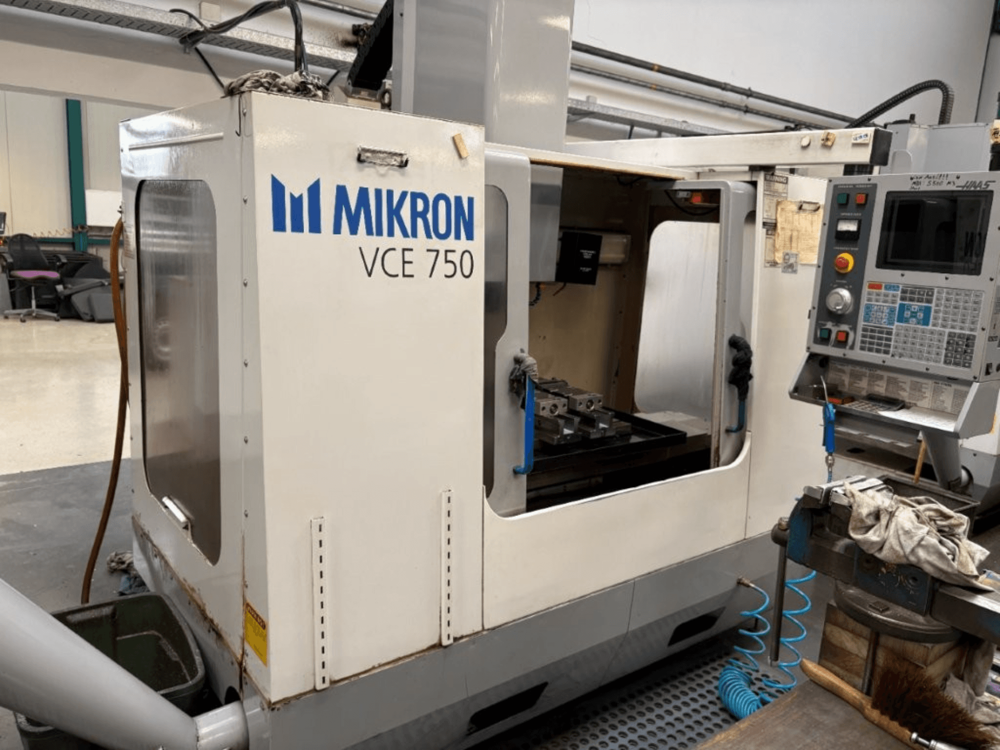 Mikron VCE 750 CNC milling machine front view, featuring a machined worktable and control panel with various buttons and screens.
