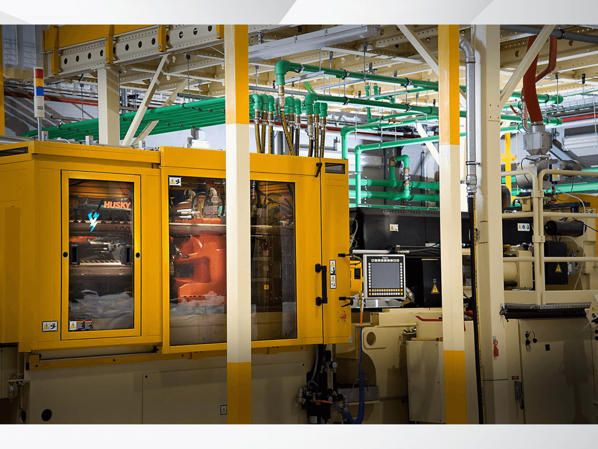 Husky industrial machine in yellow, front view showcasing control panel and internal mechanisms against a factory backdrop.