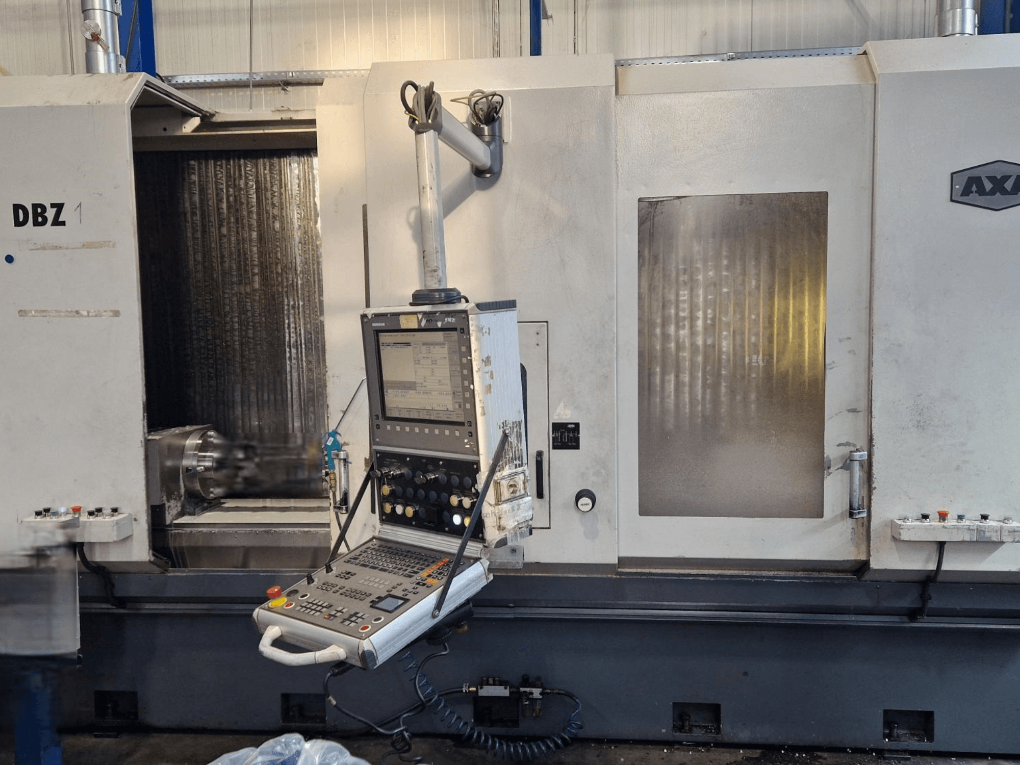 Centro de mecanizado vertical AXA DBZ mostrado desde una vista frontal en ángulo, con un panel de control y una zona de herramienta de corte visible.