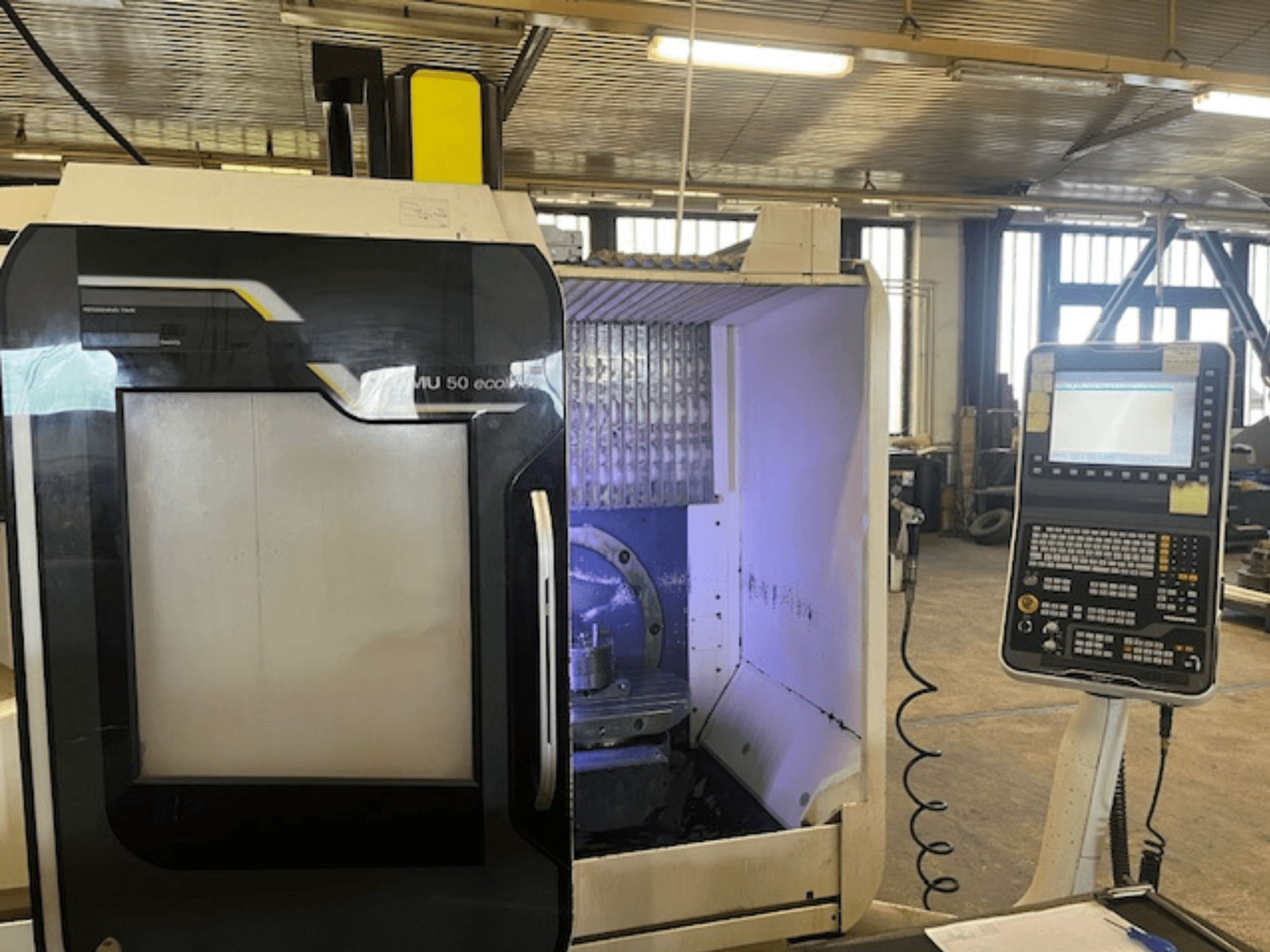 Vista frontal de la fresadora DMU 50 eco con panel de control, mostrando el portaherramientas y el espacio de trabajo.