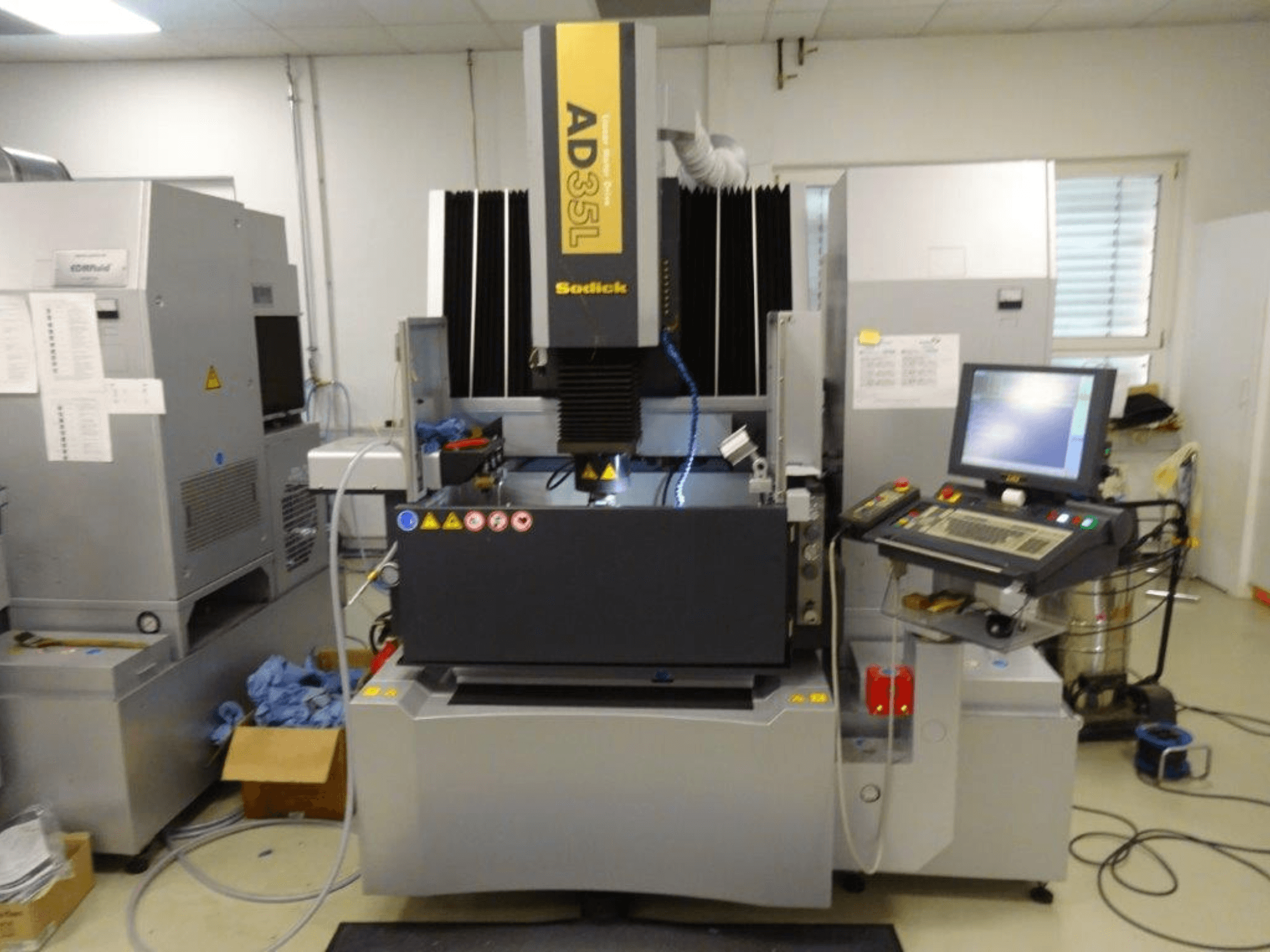 Máquina de descarga eléctrica Sodick AD35L, vista frontal con panel de control, sistema de refrigeración y área de trabajo visibles.