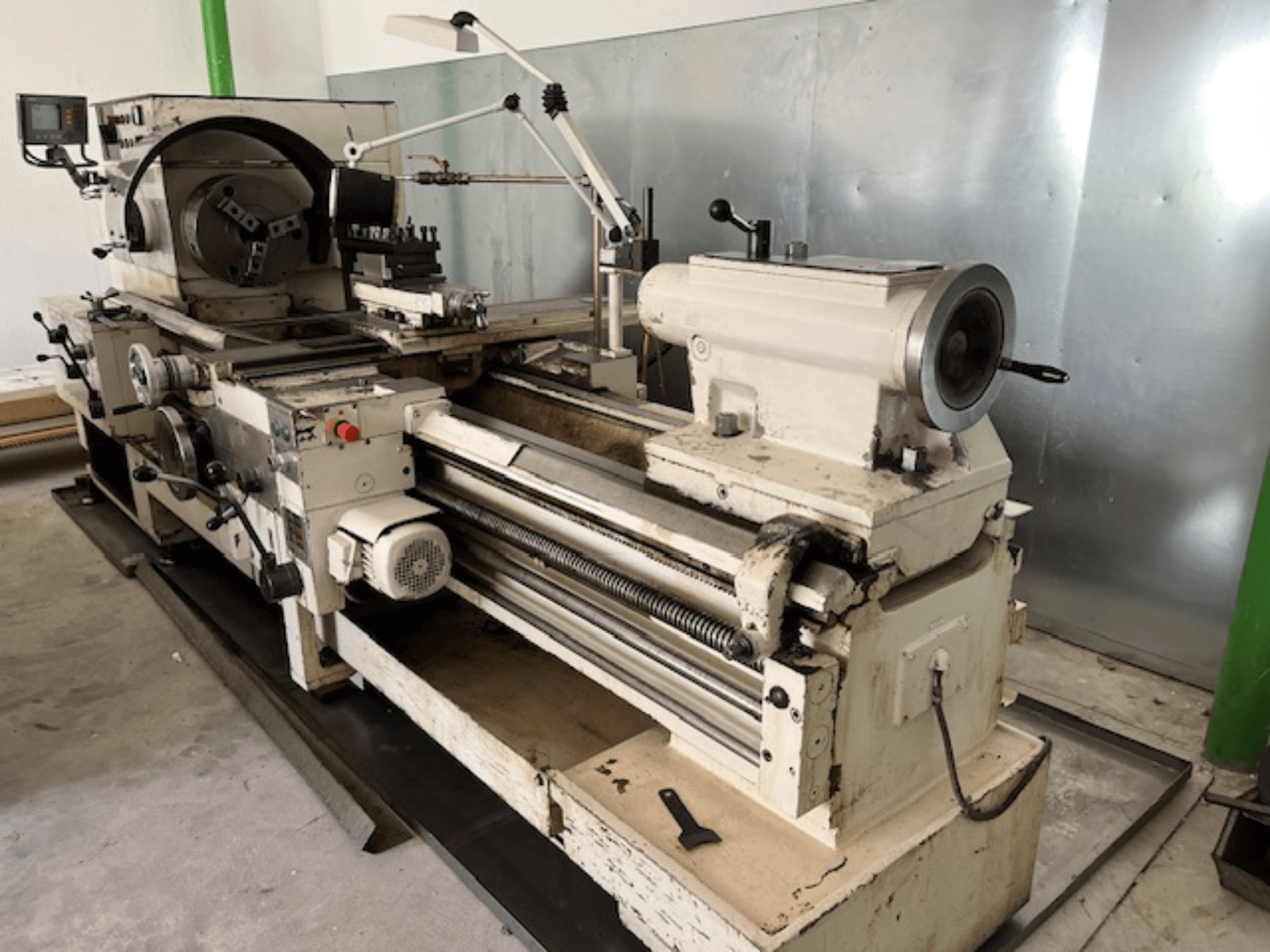 Vintage metal lathe machine with control panel and tools, side view, showing operational elements and metal finish.