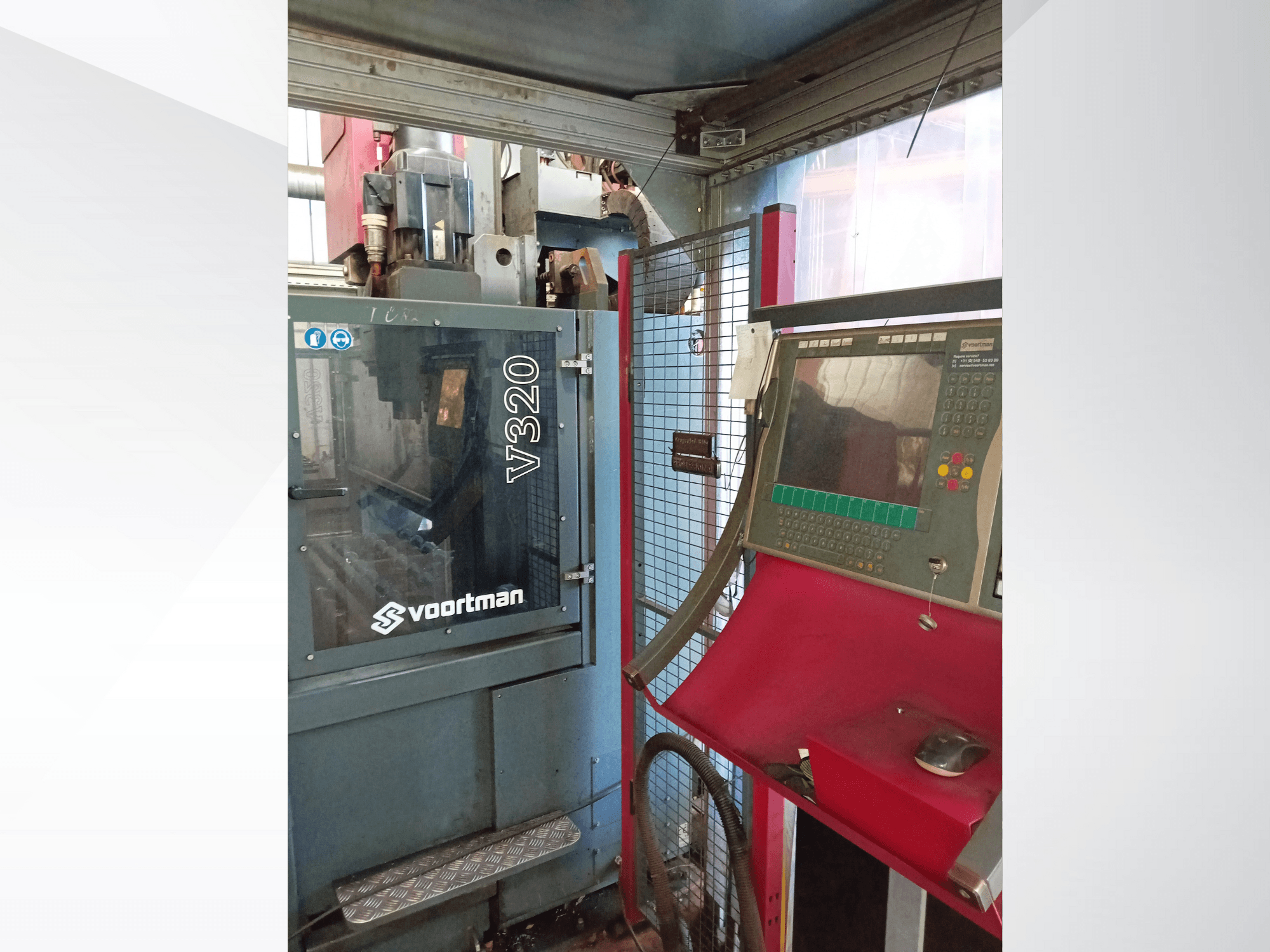 Vista frontal de la máquina CNC Voortman V320, con panel de control con botones, pantalla de visualización y carcasa de malla de seguridad.