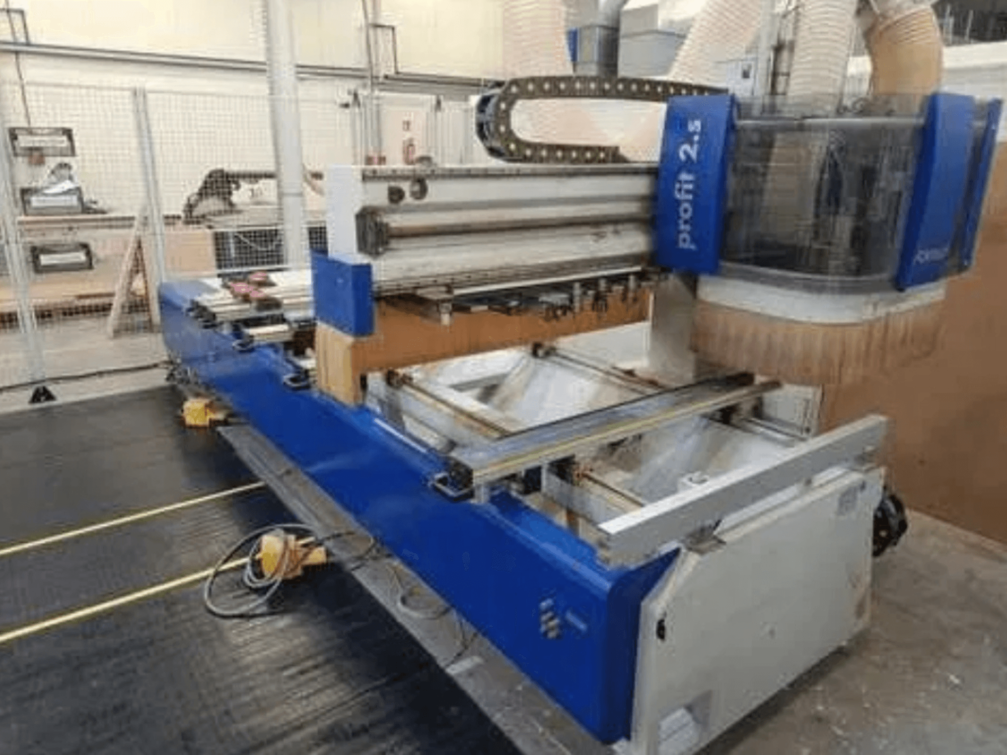 Máquina CNC, marca Profitec 2.5, la vista frontal muestra el cuerpo azul, el área de trabajo y la boquilla de extracción de polvo para el procesamiento de la madera.