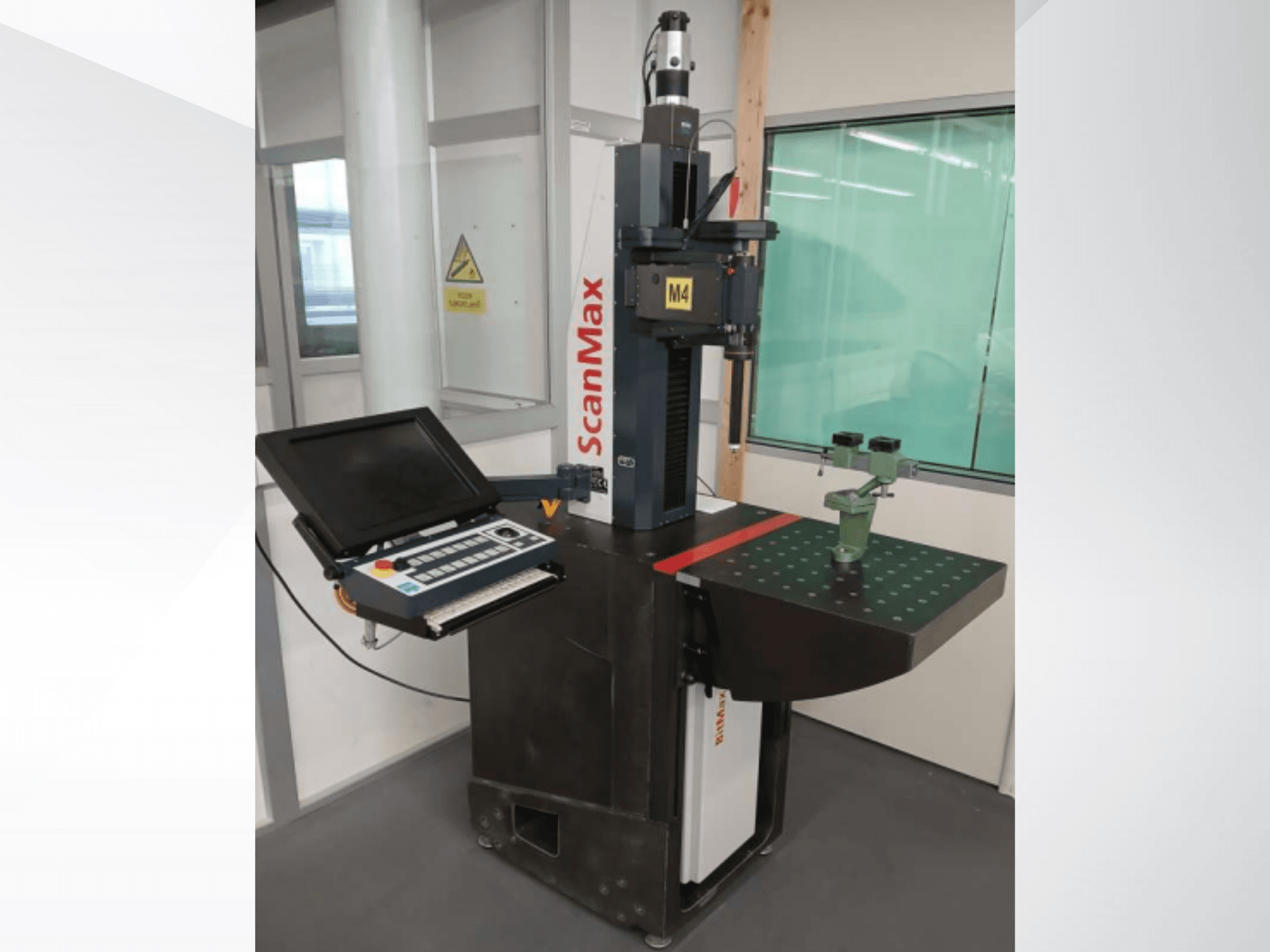 Máquina de medición ScanMax M4, vista frontal con panel de control y útil de calibración verde sobre una mesa de trabajo punteada.