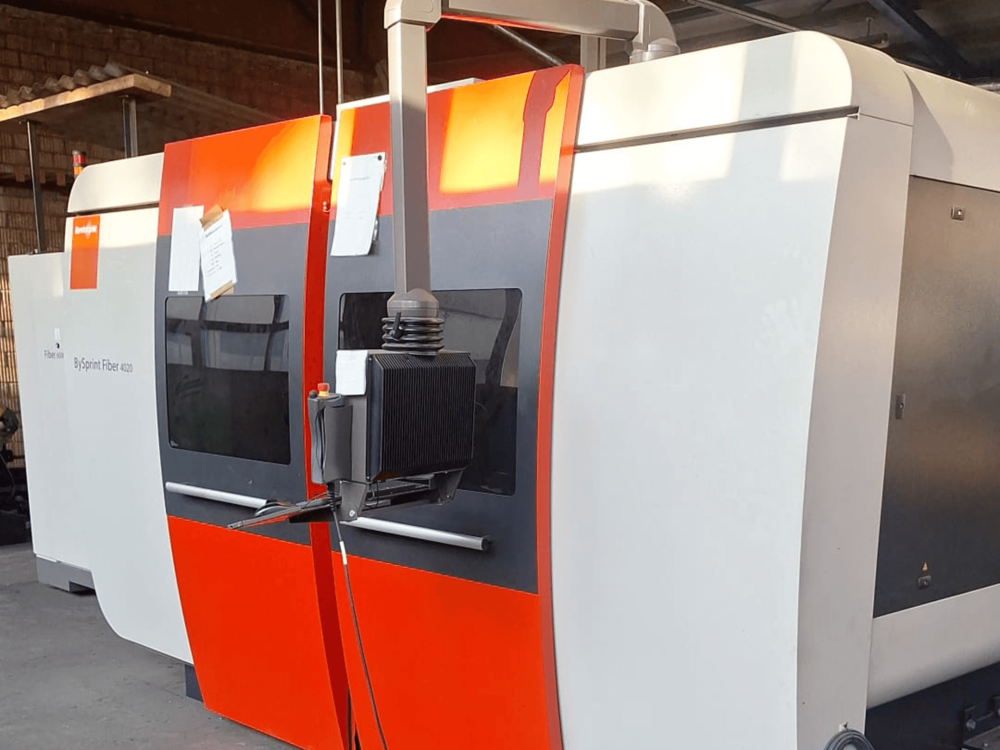 Máquina de corte por láser BySprint Fiber 4020, vista lateral, con exterior rojo y blanco, panel de control detallado visible.