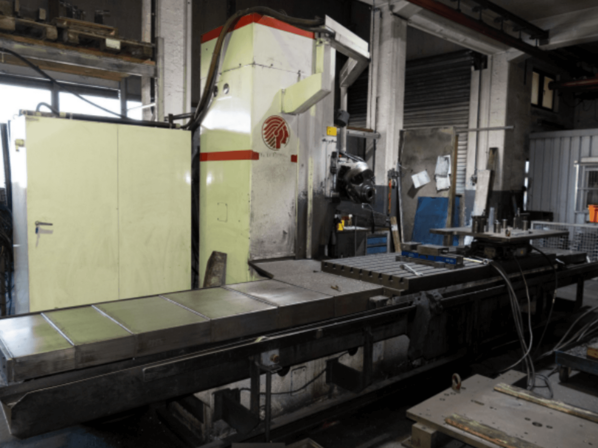 Fresadora industrial con una gran mesa, vista lateral, mostrando los controles y accesorios en un entorno de taller.