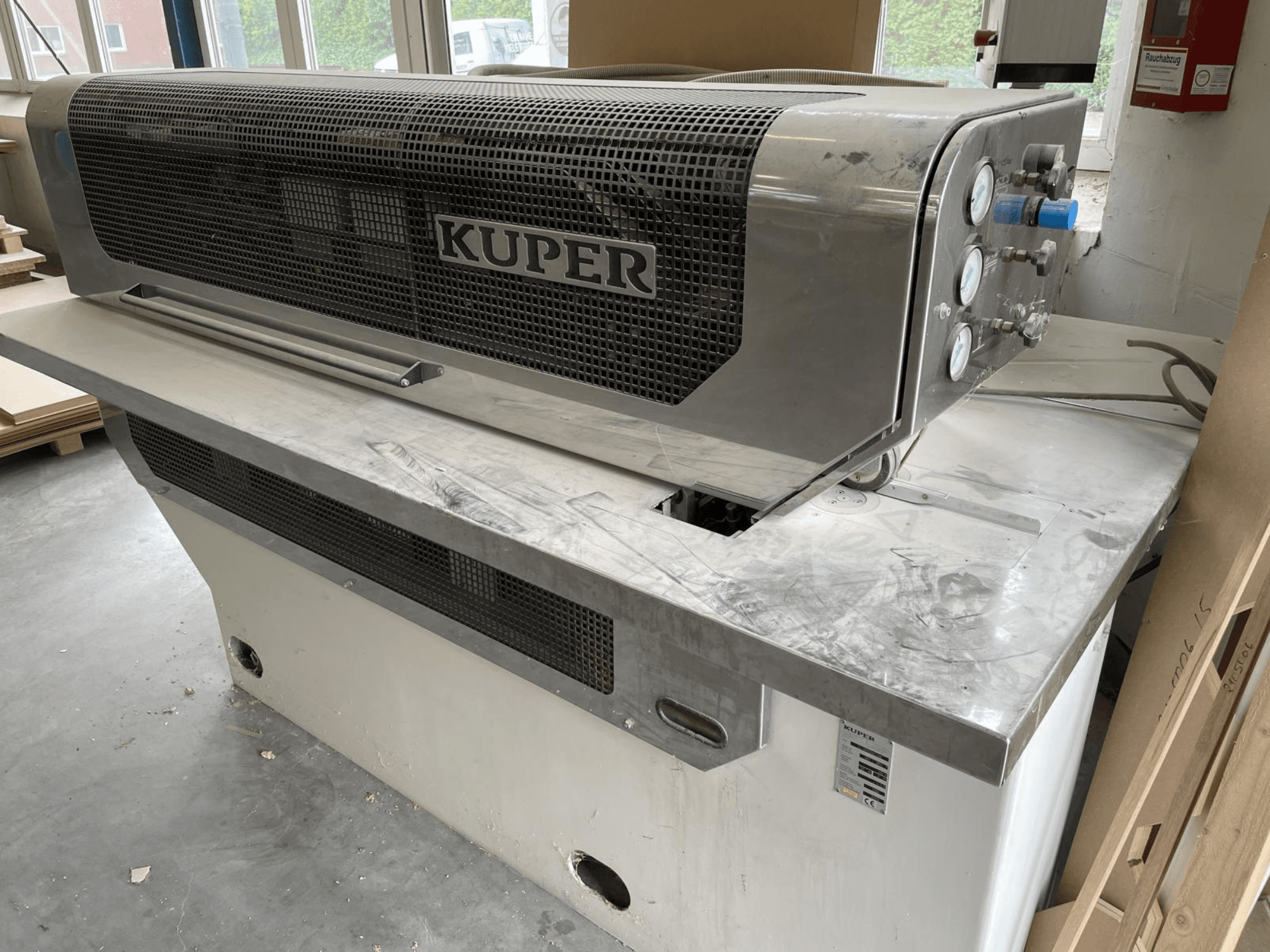 Guillotina de chapa KUPER FLI, vista frontal, con cuerpo de acero inoxidable, calibradores y zona de corte limpia en un banco de trabajo.