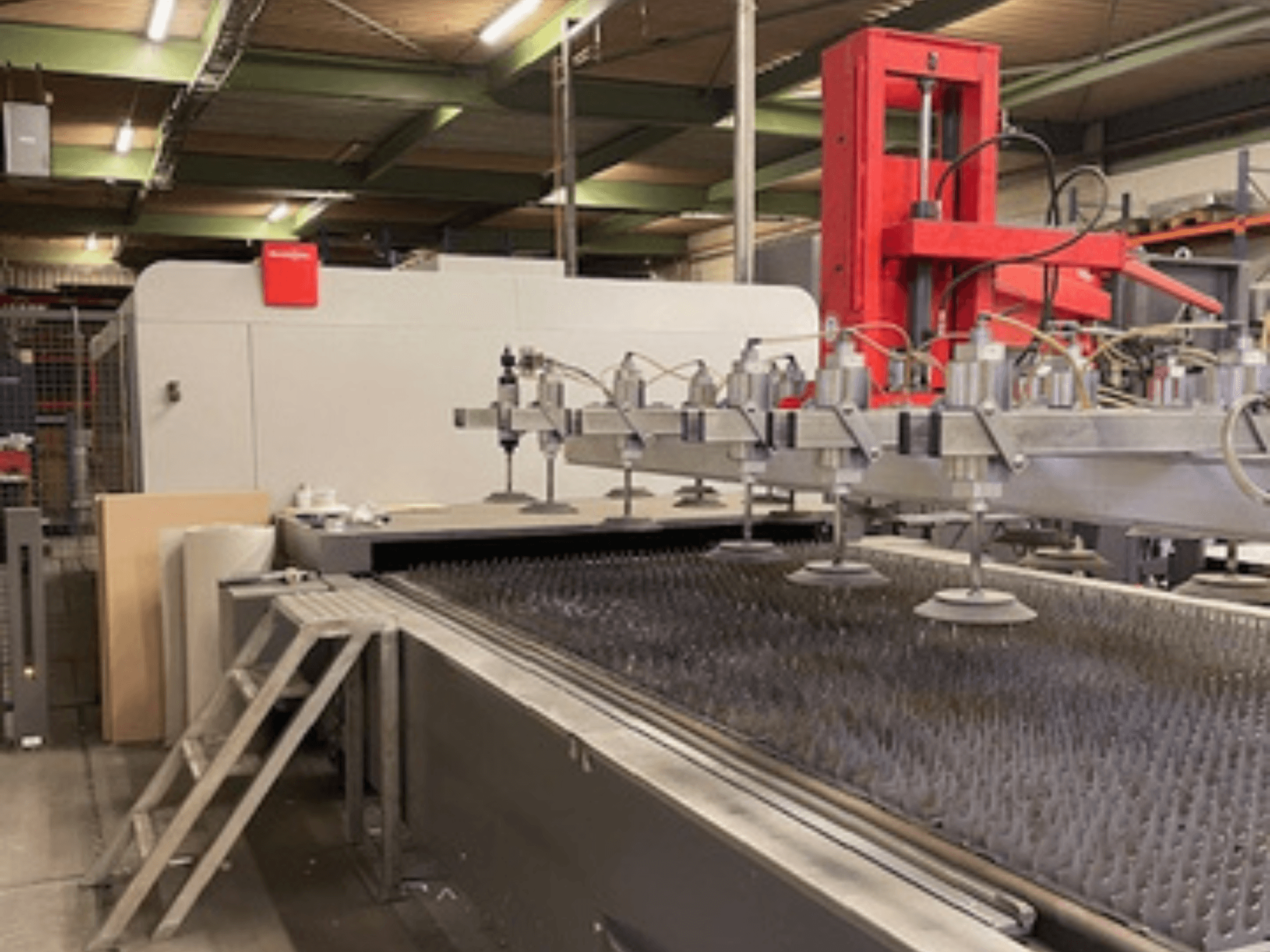 Bystronic BySprint Fiber 4020 Fiber 4Kw Vista frontal de una máquina de corte por láser de fibra con boquillas y bancada de corte.