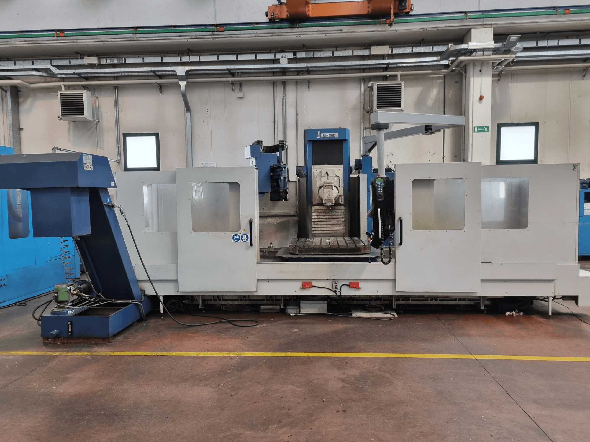 CNC milling machine by "Brembana," side view showing control panel and operational area with a work table inside.