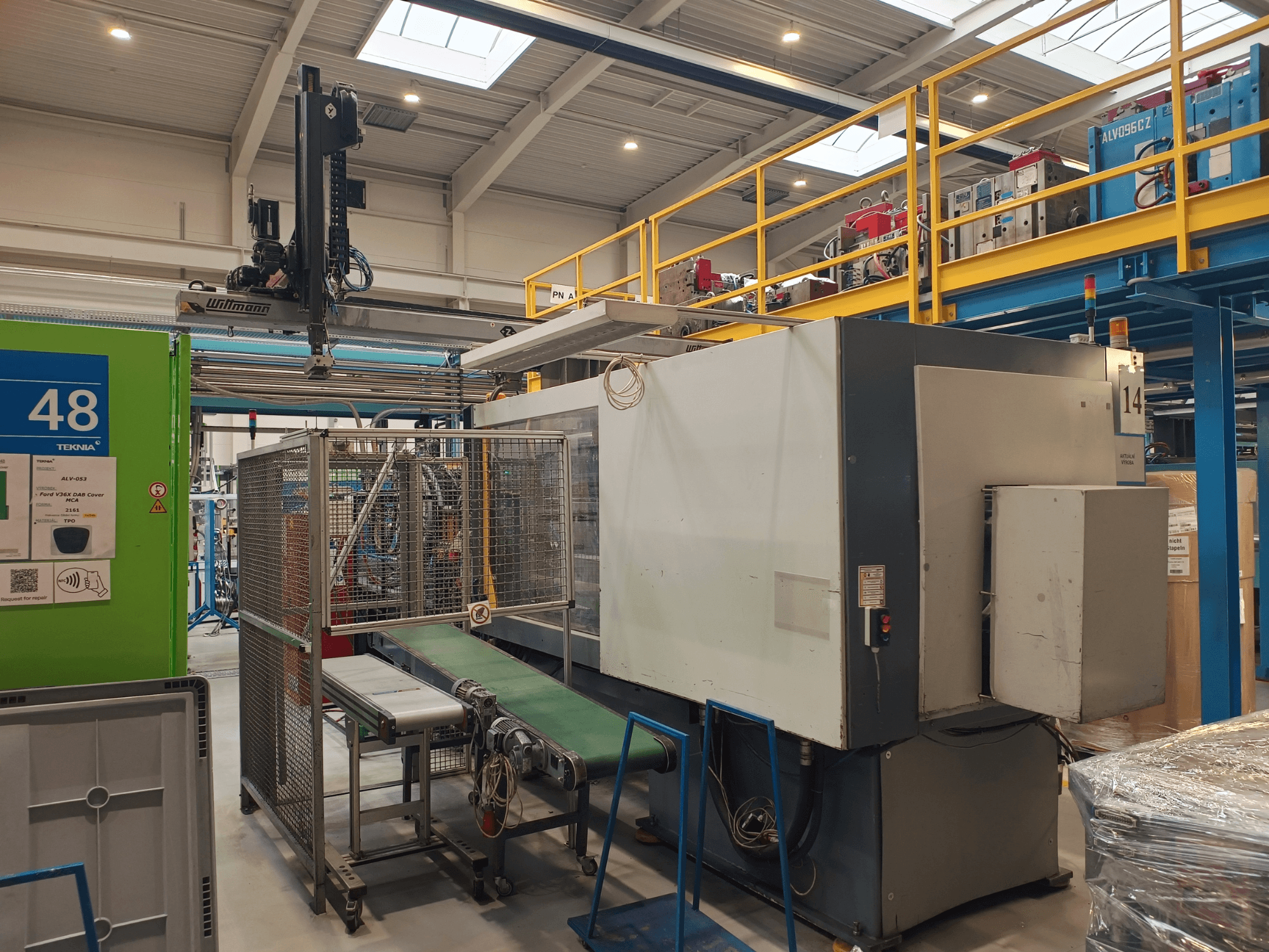 Máquina de automatización industrial de Winmon, vista lateral que muestra la cinta transportadora, el panel de control y la jaula de seguridad en un entorno de fábrica.