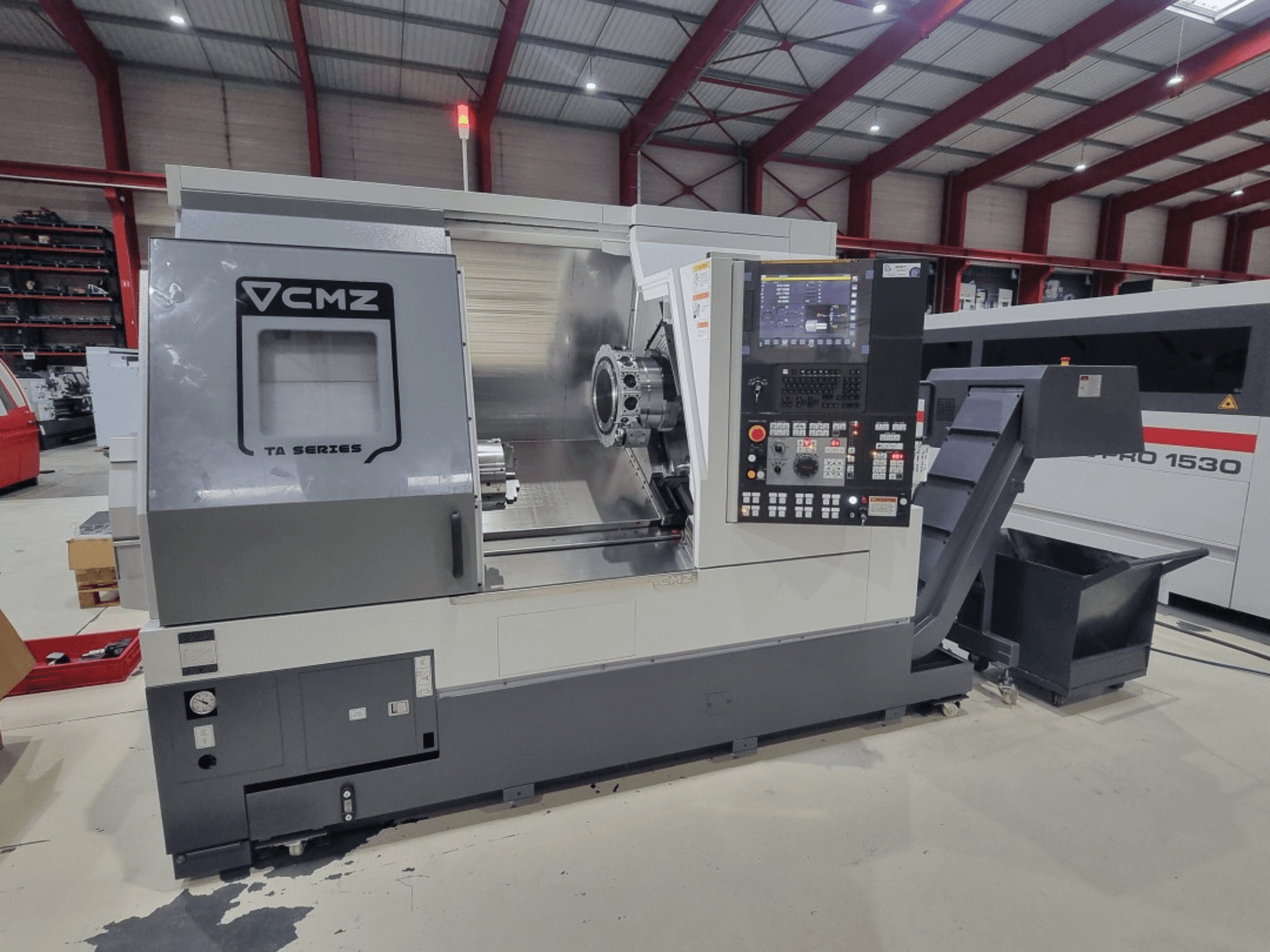 CMZ TA Series CNC lathe machine, side view, featuring control panel, work area, and shavings bin in a workshop setting.