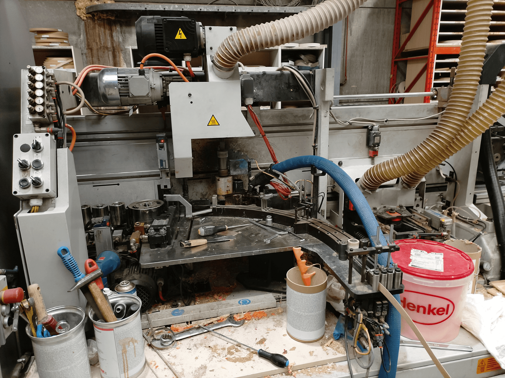 Chapadora de cantos BIESSE Edge Stram B1 en vista frontal, mostrando maquinaria, mangueras y herramientas de trabajo entre virutas de madera.