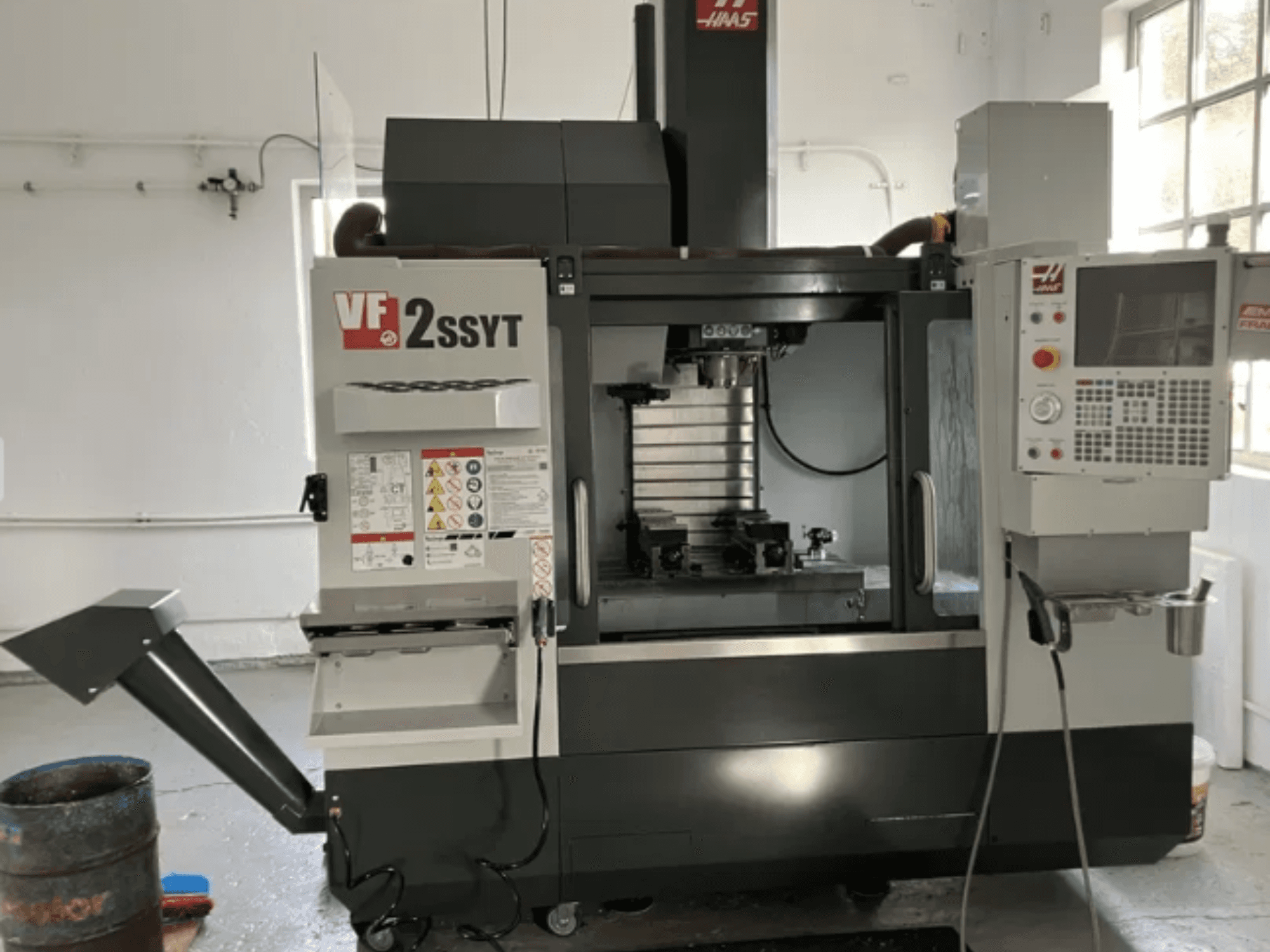 Fresadora CNC Haas VF-2SSYT, vista frontal, con panel de control, portaherramientas y sistema de refrigeración para el mecanizado de metales.