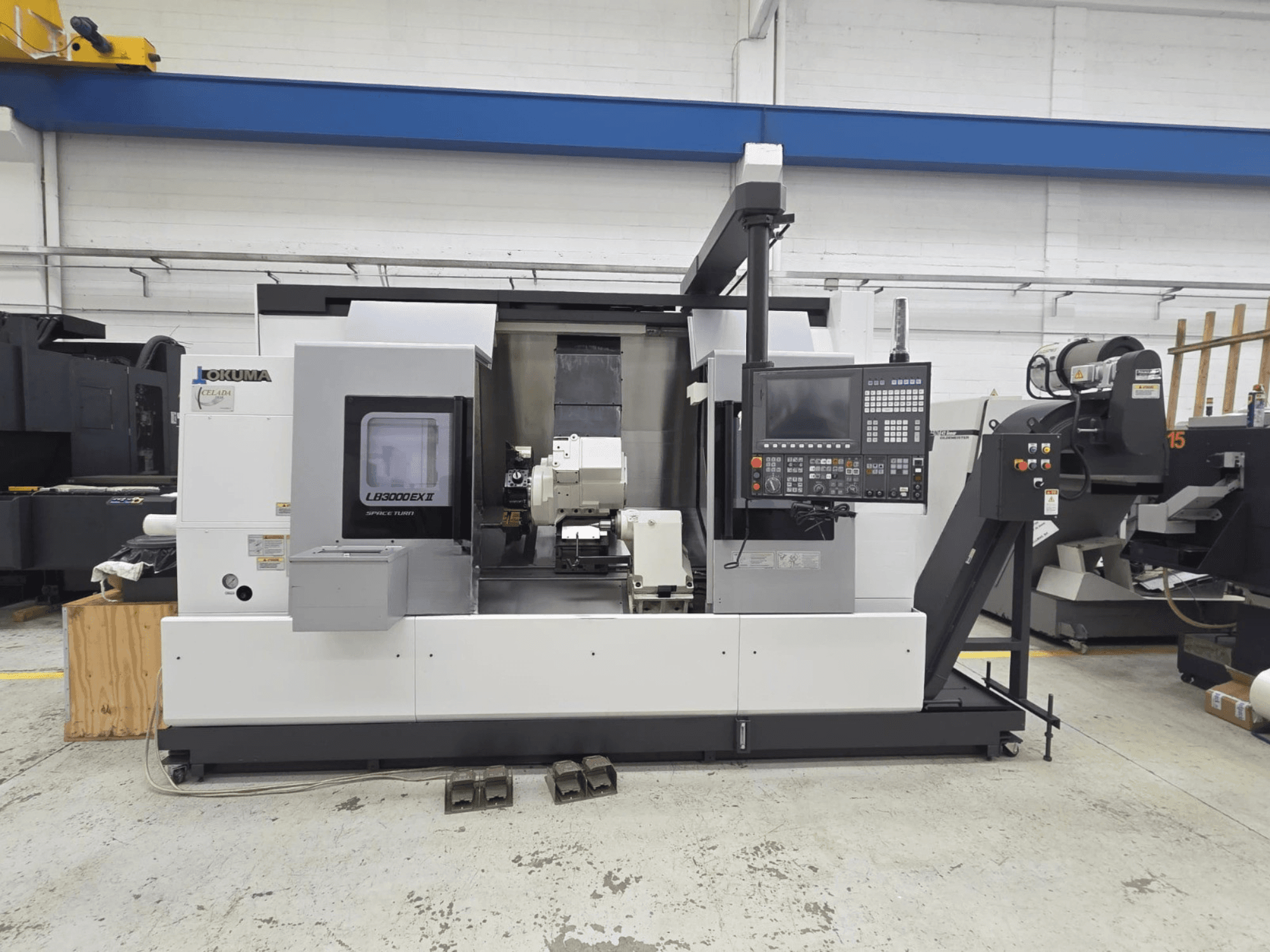 Vista frontal del torno horizontal Okuma LB 3000 EXII, con panel de control y portaherramientas.