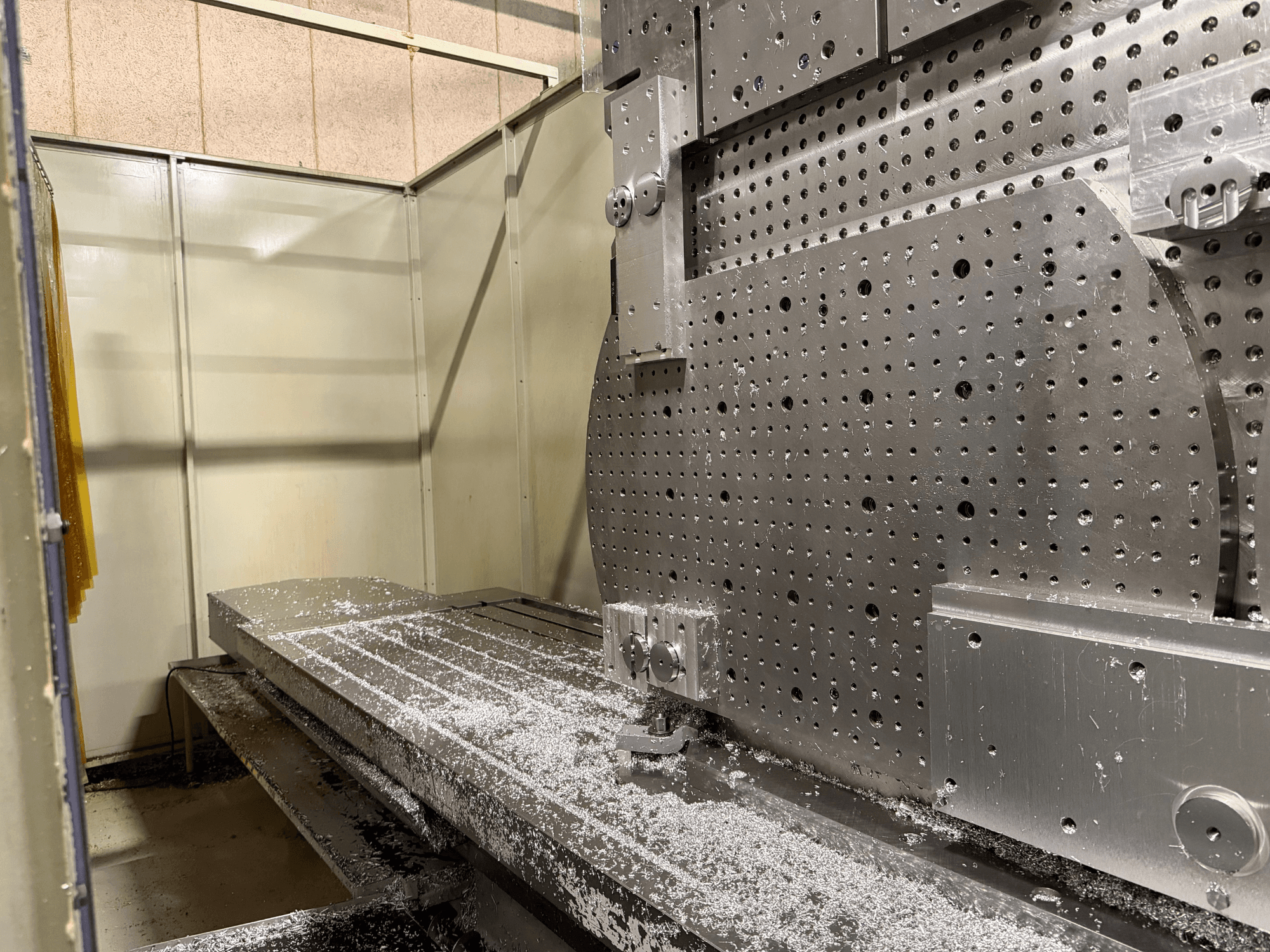 Vista frontal en primer plano del Centro de Mecanizado Universal KIHEUNG KNC-U1000, mostrando una mesa de trabajo metálica con virutas de aluminio.